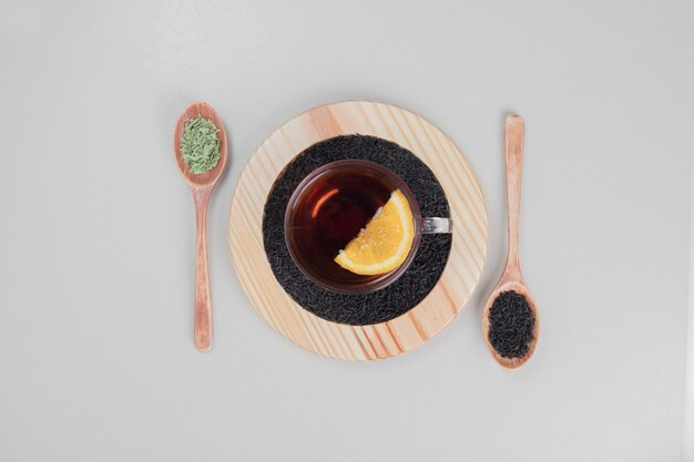 Tè caldo con cucchiai e limone sul piatto di legno