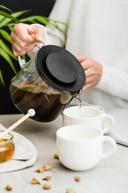 Tè di versamento della donna in tazza dal produttore di tè