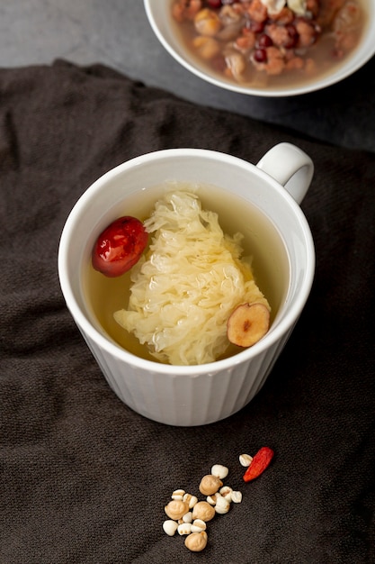 Tè in una tazza bianca e una ciotola con zuppa su un panno grigio