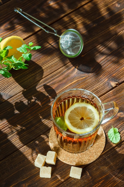 Tè in una tazza con cubetti di foglie, limone e zucchero