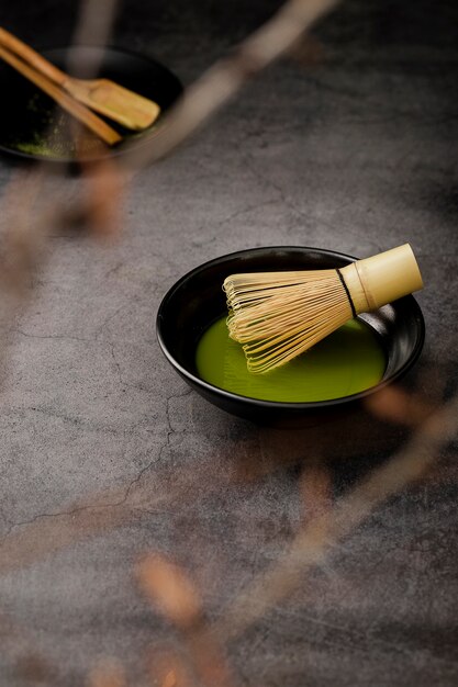 Tè matcha defocused in ciotola con frusta di bambù