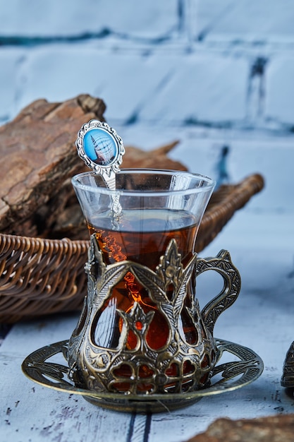 Tè nero in una tazza di vetro tradizionale e biscotti sulla tavola di legno blu