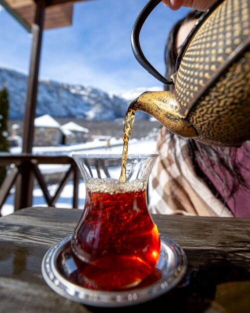 tè una donna che versa tè nero su sfondo di montagna