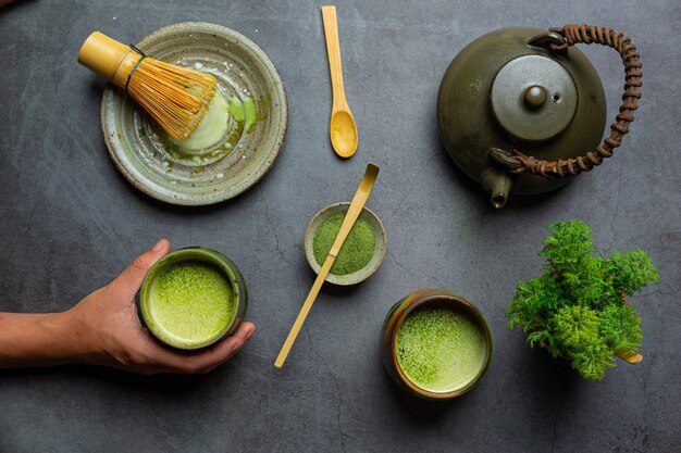 Tè verde caldo in un bicchiere con crema condita con tè verde, decorato con tè verde in polvere.