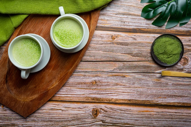 Tè verde caldo in un bicchiere con crema condita con tè verde, decorato con tè verde in polvere.