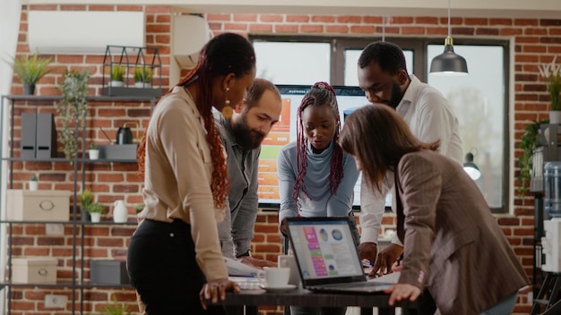 Team di colleghi che analizzano i grafici sui documenti per pianificare il progetto, lavorando insieme per progettare la presentazione per la crescita e lo sviluppo del business. Gruppo di colleghi che fanno lavoro di squadra al lavoro dell'azienda.