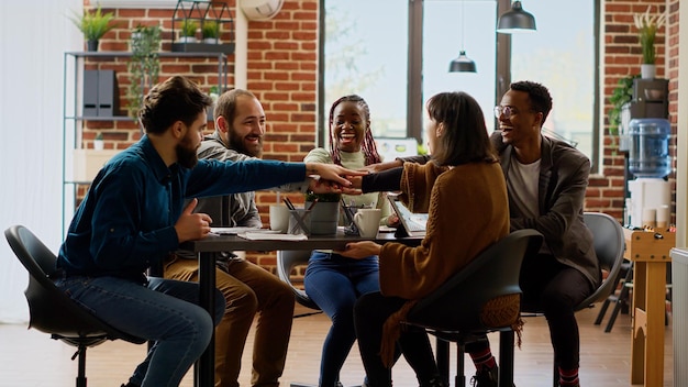 Team eterogeneo di colleghi che hanno una partnership di successo e si sentono felici del lavoro di squadra professionale. Persone allegre che celebrano insieme l'accordo di collaborazione nella riunione della sala riunioni.