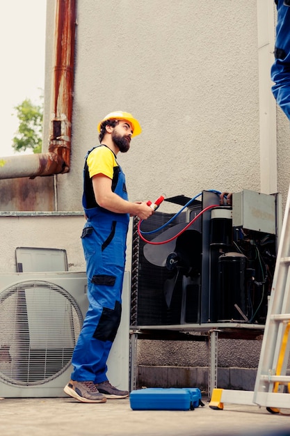 Team eterogeneo di lavoratori meticolosi che eseguono revisioni di routine del condizionatore d'aria, assemblando manometri. Meccanici competenti che controllano le perdite di freon del sistema hvac che portano a un cattivo raffreddamento