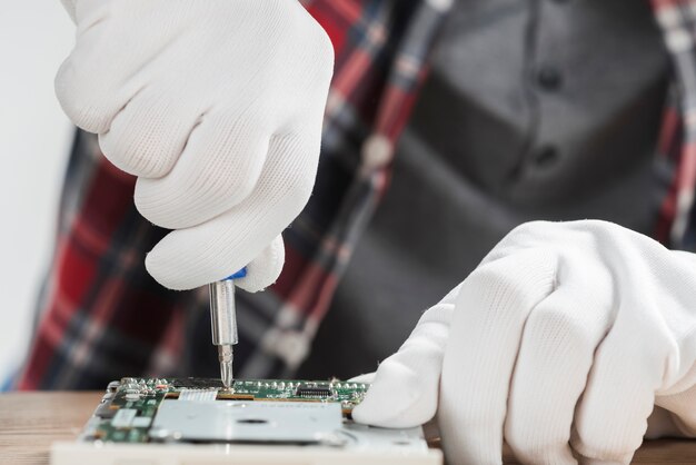 Tecnico che ripara la scheda madre del computer con il cacciavite