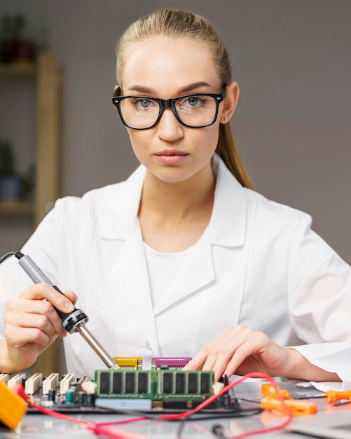 Tecnico femminile con scheda elettronica e saldatore