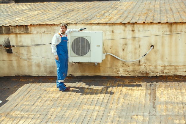 Tecnico HVAC che lavora su una parte del condensatore per l'unità motocondensante