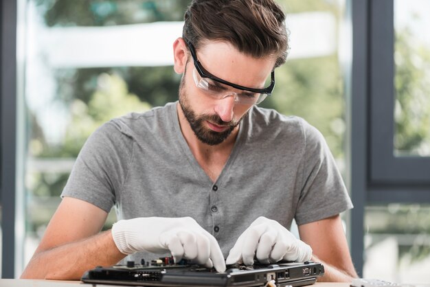 Tecnico maschio in occhiali di sicurezza che ripara computer