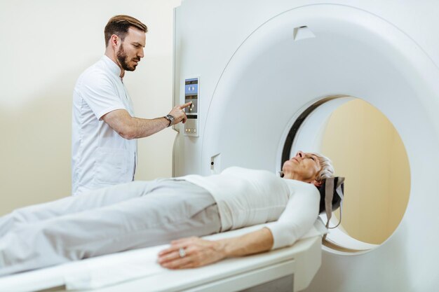 Tecnico medico che inizia la procedura di scansione MRI di un paziente maturo nella sala d'esame