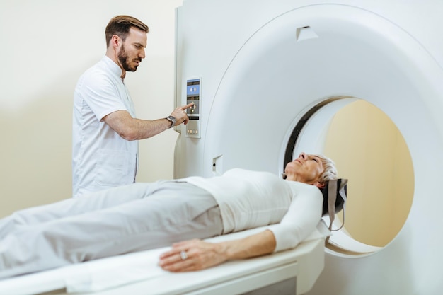 Tecnico medico che inizia la procedura di scansione MRI di un paziente maturo nella sala d'esame