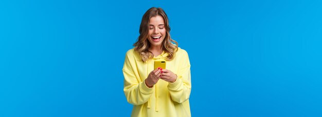 Tecnologia e concetto di persone ragazza bionda sorridente felice che utilizza il telefono cellulare in caso di messaggistica gialla l