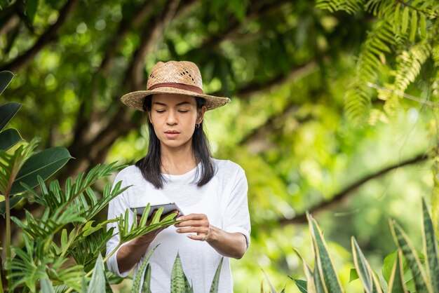 Tecnologia moderna nel settore del giardinaggio. giovane donna con tavoletta digitale che lavora in un centro di giardinaggio. ambientalista utilizzando tavoletta digitale. donna giardinaggio fuori nella natura estiva.