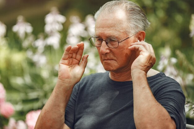 Tecnologia, persone e concetto di comunicazione. Uomo maggiore al parco estivo. Nonno usando un telefono.