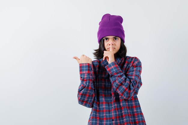 Teen donna in camicia a scacchi e berretto gesticolando isolato