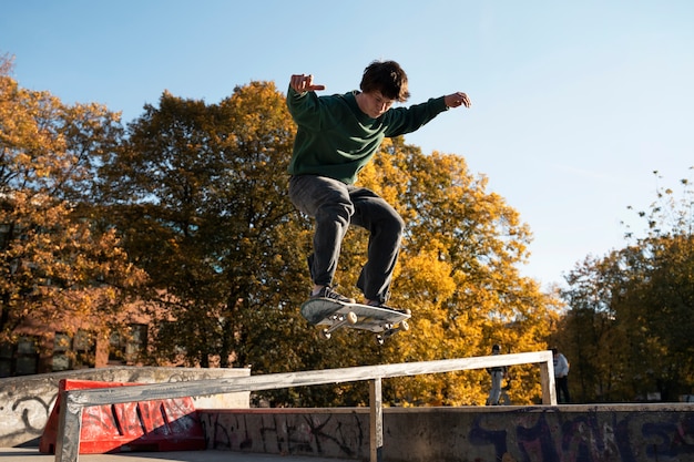Teenager che fa i trucchi sul colpo pieno dello skateboard