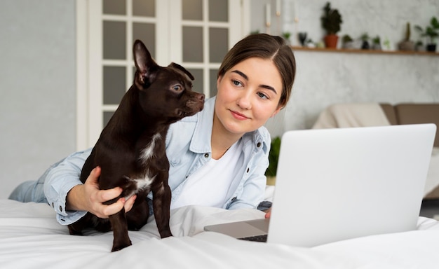 Teenager del colpo medio a letto con laptop e cane