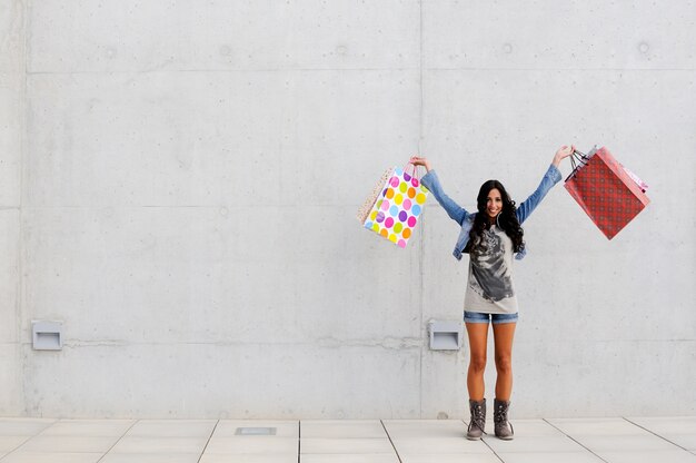 Teenager felice con le mani piene di sacchetti