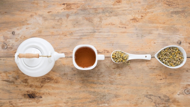 Teiera; tè al limone e fiori secchi di crisantemo cinese disposti in fila sul tavolo