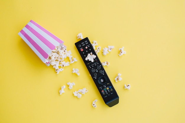 Telecomando della TV vicino a popcorn rovesciato