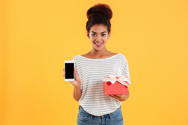 Telefono della tenuta della giovane signora con lo schermo e il presente in bianco