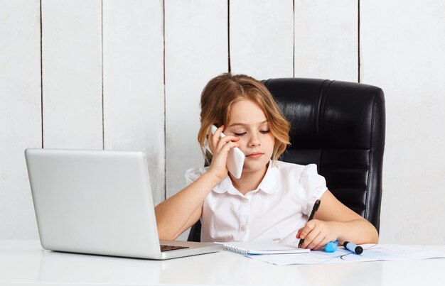 Telefono parlante della giovane bella ragazza al posto di lavoro in ufficio.