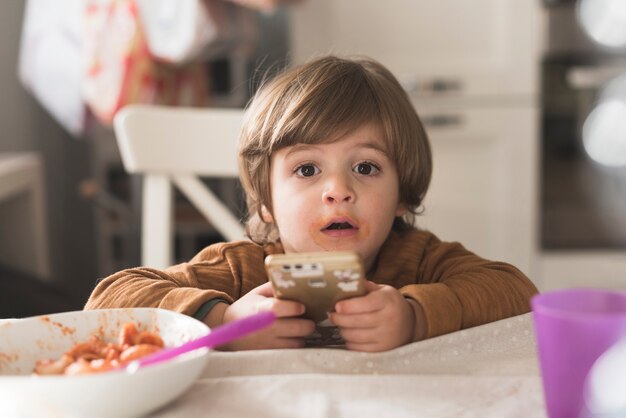 Telefono sveglio della tenuta del bambino alla tavola