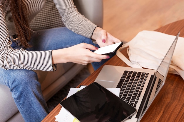 Telelavoro della donna di alta vista e telefono cellulare usando