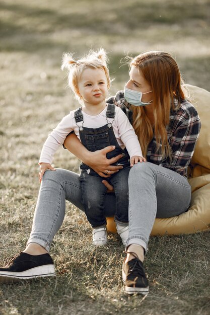 Tema Coronavirus. Famiglia in un parco estivo. Donna in una camicia di cella.