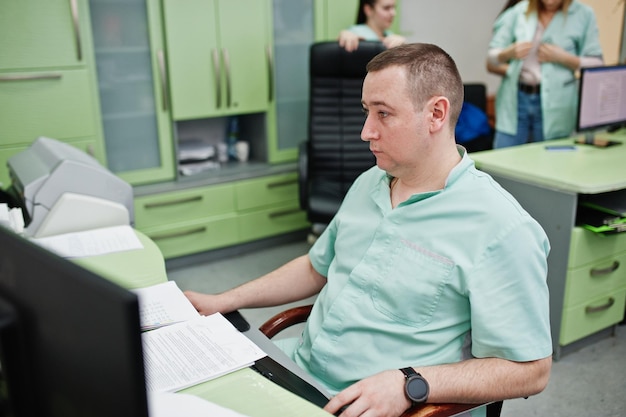 Tema medico Dottore nell'ufficio di risonanza magnetica presso il centro diagnostico in ospedale seduto vicino a monitor di computer