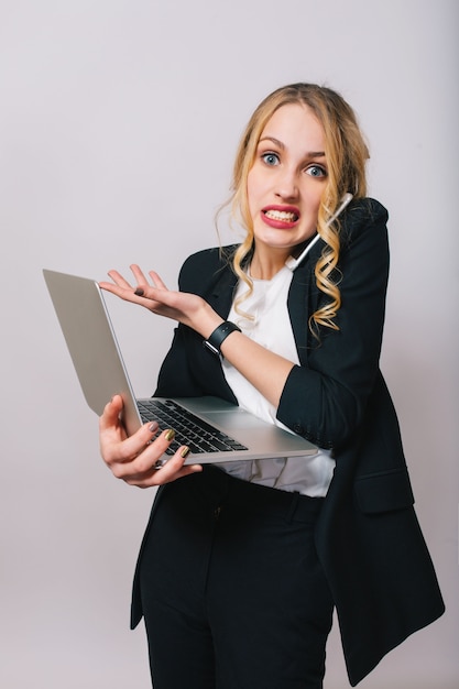 Tempo di lavoro d'ufficio occupato di giovane donna bionda divertente stupita in camicia bianca e giacca nera che sembra isolata. Parlando al telefono, lavorando con laptop, lavoratore, lavoro, manager