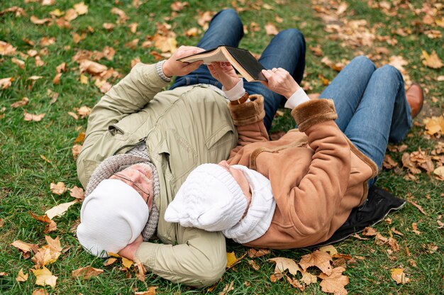 Tempo senior delle coppie da leggere mentre sedendosi sul campo con le foglie