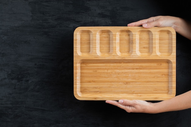 Tenendo un piatto di legno quadrato con le mani