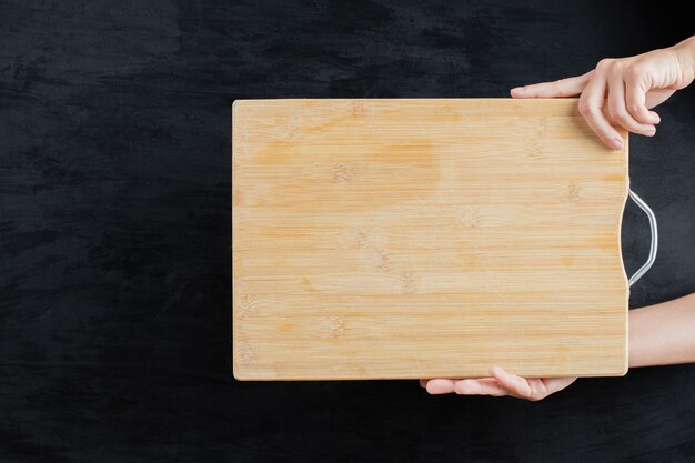 Tenendo una tavola di legno quadrata su sfondo nero