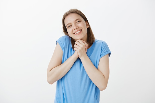 Tenera e adorabile giovane donna stringe le mani insieme, sorridendo grata, riceve un regalo