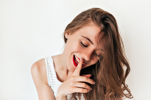 Tenerezza bella giovane donna con agitando i capelli e le labbra rosse mette un dito sulle labbra