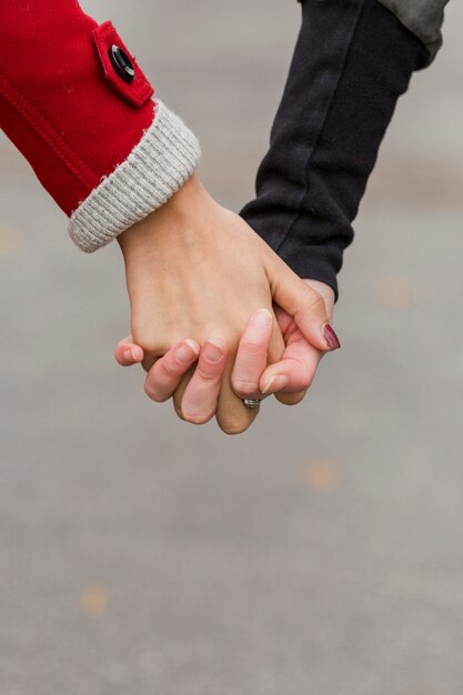 Tenersi per mano delle mani delle giovani donne del primo piano