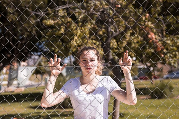 Tenuta della ragazza sulla griglia del metallo