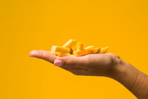 Tenuta delle patate fritte davanti a fondo giallo