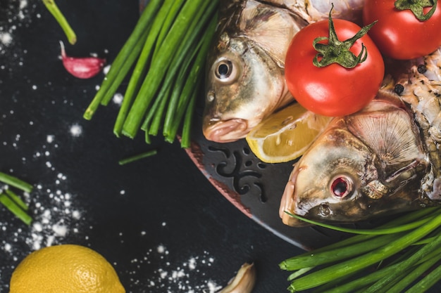 Teste di pesce con erbe aromatiche, limone e pomodori con sale marino intorno