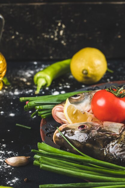 Teste di pesce crudo con verde, limone e pomodori