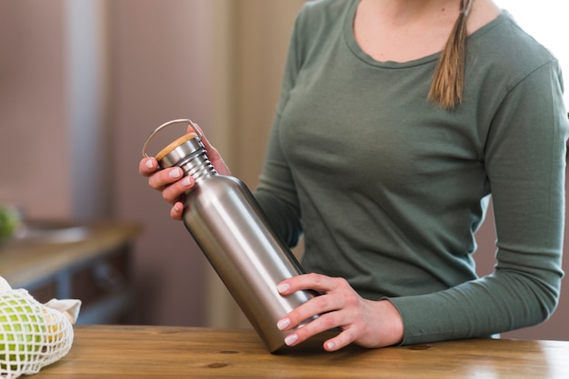 Thermos del caffè della tenuta della donna del primo piano