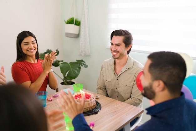 Ti auguriamo molti altri compleanni. Amici affettuosi che applaudono e cantano buon compleanno a un bel giovane. Amici che partecipano a una festa di compleanno