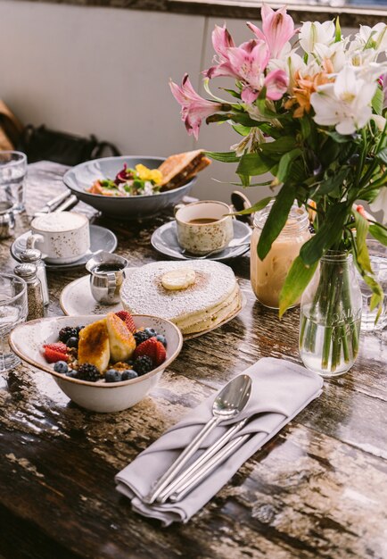 Tipi di cibi, biscotti e bevande messi sul tavolo davanti al vaso di fiori