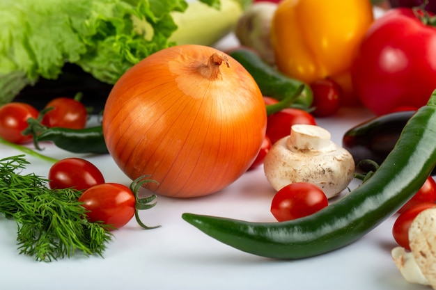 Tipi differenti delle verdure variopinte di verdure di insalata sul pavimento bianco