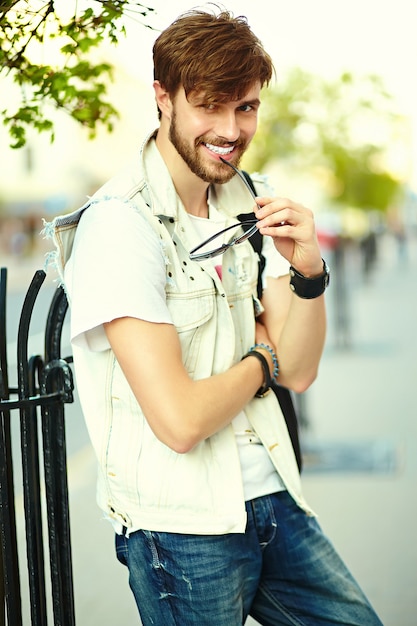 Tirante bello sorridente divertente dell'uomo bello dei pantaloni a vita bassa in panno alla moda di estate nella via in occhiali da sole