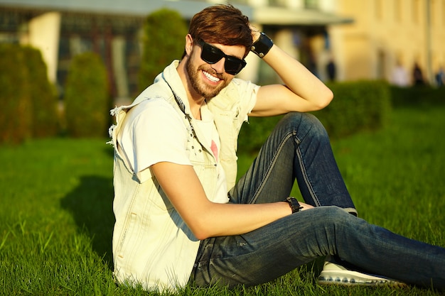 Tirante bello sorridente divertente dell'uomo bello dei pantaloni a vita bassa in panno alla moda di estate nella via in occhiali da sole